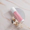 Pink and white Dr. Esthe cosmetic tube on a marble surface with dried flowers