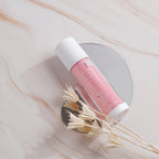 Pink and white Dr. Esthe cosmetic tube on a marble surface with dried flowers