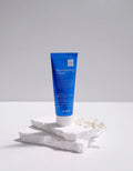 Blue tube of 'Rejuvenating Cream' on a white surface with a gray background