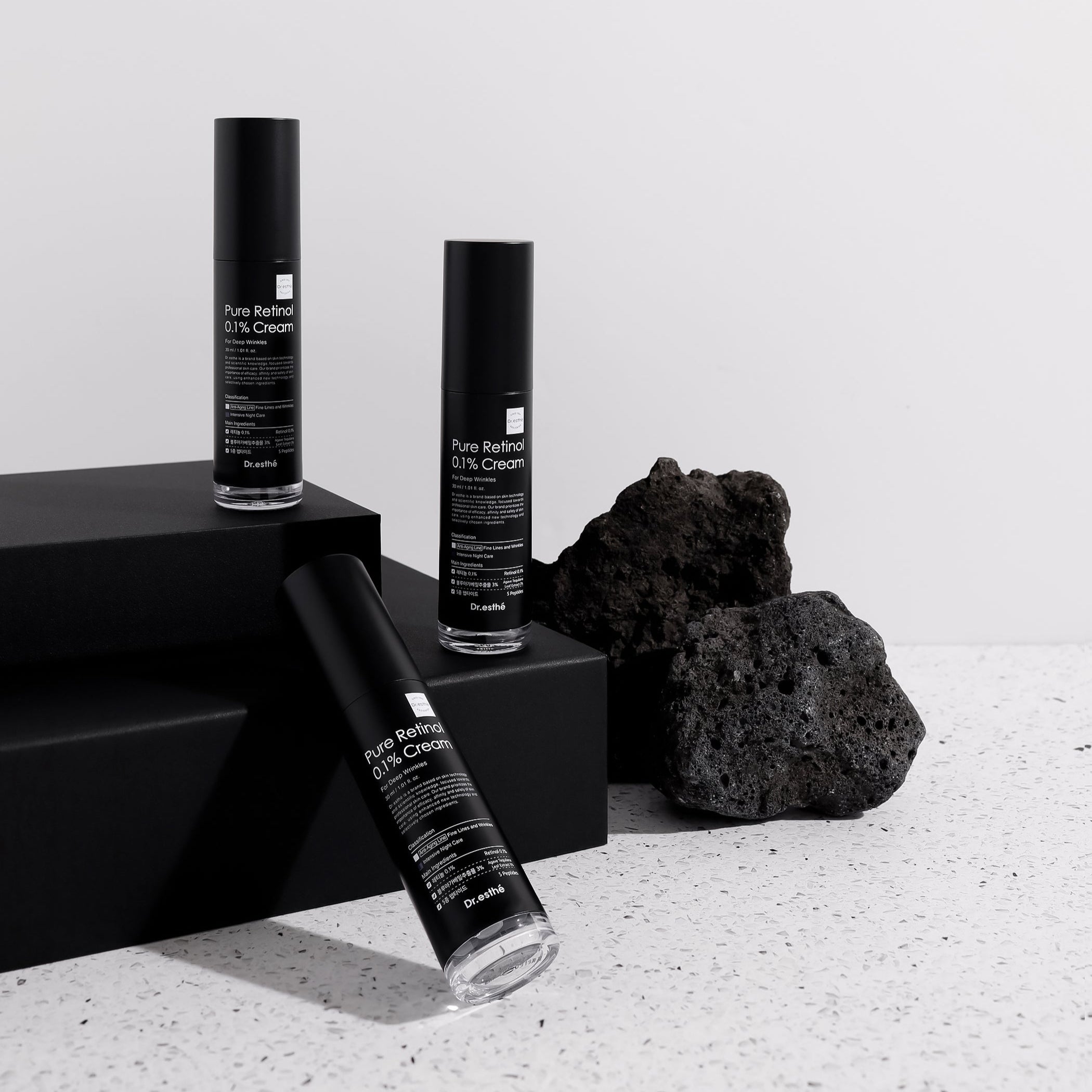 Three black Dr. Esthe retinol skincare bottles with labels on a light gray background