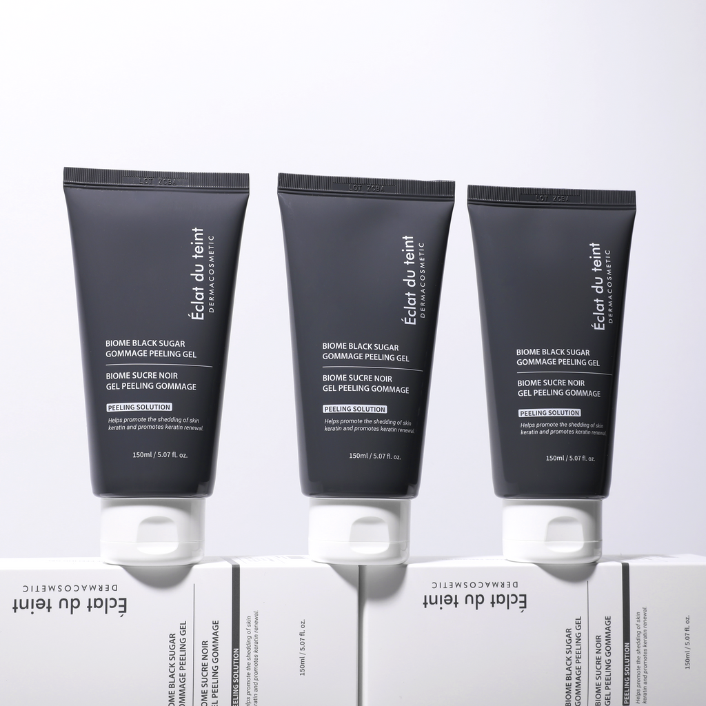 Three black tubes of Eclat du Teint skincare product Biome black sugar gommage peeling gel on a white background